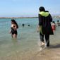 In this Aug. 4 2016, file photo made from video, Nissrine Samali, 20, gets into the sea wearing traditional Islamic dress, in Marseille, southern France. The French resort of Cannes has banned full-body, head-covering swimsuits worn by some Muslim women from its beaches, citing security concerns. A City Hall official said the ordinance, in effect for August, could apply to burkini-style swimsuits. (AP Photo, File)