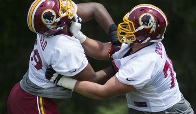 Washington Redskins offensive linemen Takoby Cofield, left, and Brandon Scherff take part in a drill during an NFL football organized team activity at Redskins Park, on Tuesday, May 26, 2015, in Ashburn, Va. (AP Photo/Evan Vucci)