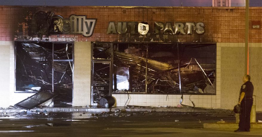 Police stand watch over the burned out remains of an O'Reilly Auto Parts store, early Sunday, Aug. 14, 2016, near N. 35th Street and W. Burleigh Street in Milwaukee. After a police officer shot and killed an armed suspect after a foot chase, a gas station, a beauty supply store, a bank and an auto parts store were set ablaze in violence related to the shooting. (Mark Hoffman/Milwaukee Journal-Sentinel via AP)