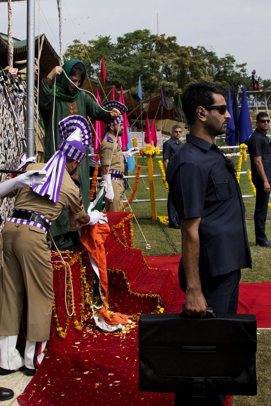 Jammu and Kashmir state Chief Minister Mehbooba Mufti, in green dress, watches as she holds the rope attached to India's national flag after it fell during the unfurling ceremony on India's Independence Day in Srinagar, Indian controlled Kashmir, Monday, Aug. 15, 2016. Authorities ordered a probe to ascertain if it was a sabotage or negligence after India's national flag fell on the top elected official as she pulled the rope to unfurl the flag at the highly guarded soccer stadium. (AP Photo/Dar Yasin)