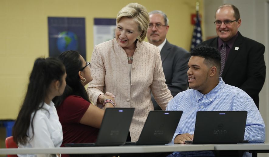 Democratic presidential candidate Hillary Clinton talks with students as she tours classrooms at John Marshall High School in Cleveland, Wednesday, Aug. 17, 2016, before participating in a campaign event. Standing behind Clinton at right is Eric Gordon, Chief Executive Officer, Cleveland Metropolitan School District, and David Quolke, President, Cleveland Teachers Union, second from right. (AP Photo/Carolyn Kaster)