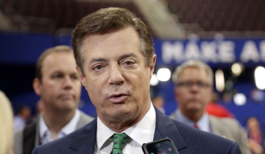 Then-Trump campaign chairman Paul Manafort talks to reporters on the floor of the Republican National Convention at Quicken Loans Arena in Cleveland on July 17, 2016, as Rick Gates listens at back left. (Associated Press) **FILE**