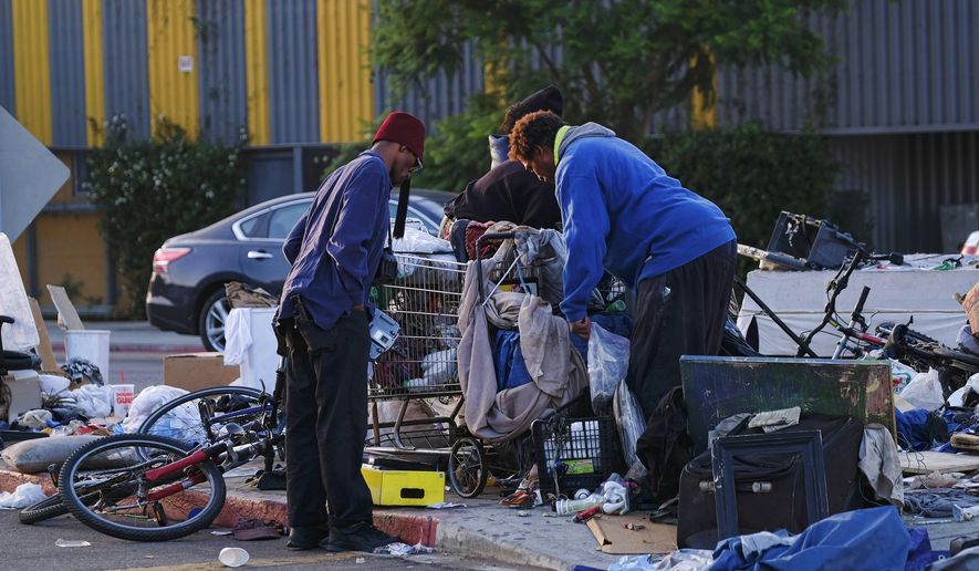 Homeless men sort through their belongings on a traffic island near downtown Los Angeles on Thursday, Aug. 18, 2016. With two weeks left in the state legislative session, county officials from across California continued Wednesday to press Gov. Jerry Brown to declare homelessness a state of emergency. (AP Photo/Richard Vogel)