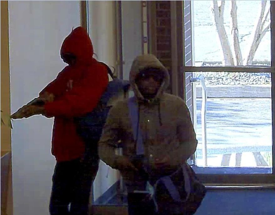 In this Thursday, Aug. 18, 2016, WellsFargo Bank security camera image released by the FBI shows two armed men robbing a bank Thursday morning on Anchorage's east side. One man was armed with a shotgun and the other with a handgun. The men at 10:14 a.m. entered the Wells Fargo Bank at 630 E. Fifth Avenue and demanded money.They carried off cash in a duffel bag with purple straps and left on foot. Witnesses say both were African-American and both wore sunglasses. One wore a red sweat shirt. The other wore a gray sweat shirt and red shoes. ( WellsFargo/FBI via AP)
