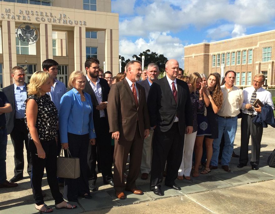 Mikal Watts (black suit, center right) and his brother's lawyer Michael McCrum (brown suit, center left) discuss acquittals Thursday, Aug. 18, 2016, outside the Gulfport, Miss., federal courthouse in a case alleging Mikal and David Watts and others had falsified a list of clients to sue BP after the 2010 Gulf of Mexico spill. The Watts brothers and three others were acquitted on 66 charges, while two people who ran the Mississippi office seeking clients were convicted on all charges (Hugh Keeton/WLOX-TV via AP)