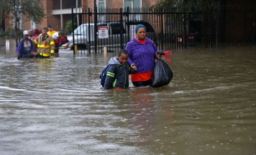 Residents wade through floodwaters from heavy rains in the Chateau Wein Apartments in Baton Rouge, La., on Aug. 12. (Associated Press)
