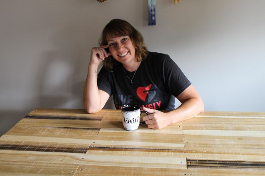 ADVANCE FOR USE SUNDAY, AUG. 21 - In this recent photo, furniture maker Cindy Hayes poses in Kearny, Neb. Hayes spends her evenings and weekends turning reclaimed wood and old pallets into furniture and wall decor. She said she researched several ideas and styles of Pinterest projects before digging through piles of wood at the landfill. (Heather Riggleman/The Daily Hub via AP) MANDATORY CREDIT