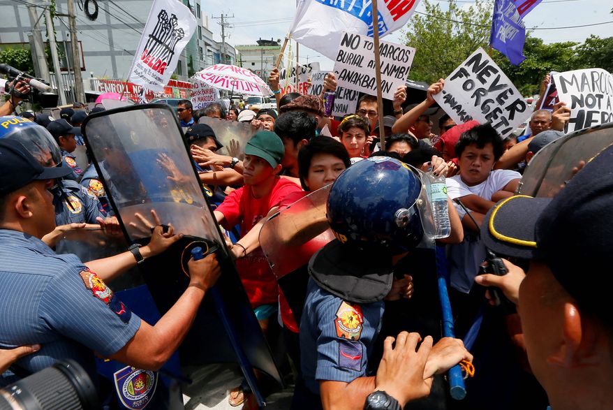 Police scuffle with protesters trying to force their way toward the gates of the Heroes' Cemetery east of Manila to oppose the scheduled burial next month of former Philippine dictator Ferdinand Marcos. (Associated Press)