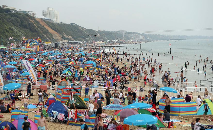 FILE - In this Thursday Aug. 18, 2016, file photo, people gather on a public beach in Bournemouth, England. Global travel spending is still growing, although at a slower pace, despite weakening economies and fears over terrorism, according to a report Monday, Aug. 22, 2016, by the World Travel and Tourism Council. Growth in the United Kingdom is actually expected to exceed the rest of Europe, in 2016. (Andrew Matthews/PA via AP, File)
