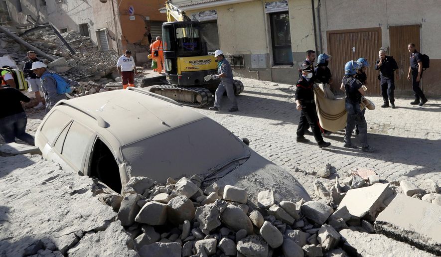 A body is carried away as a car is covered in rubble after an earthquake, in Amatrice, central Italy, Wednesday, Aug. 24, 2016. A devastating earthquake rocked central Italy early Wednesday, collapsing homes on top of residents as they slept. At least 23 people were reported dead in three hard-hit towns where rescue crews raced to dig survivors out of the rubble, but the toll was expected to rise as crews reached homes in more remote hamlets. (AP Photo/Alessandra Tarantino)
