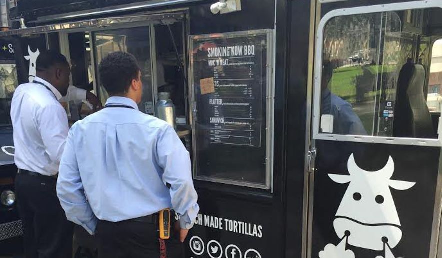 Customers check out the menu at the Smoking Kow Barbeque food truck in Farragut Square. A second Smoking Kow truck is expected late this summer. (Julia Porterfield /The Washington Times)