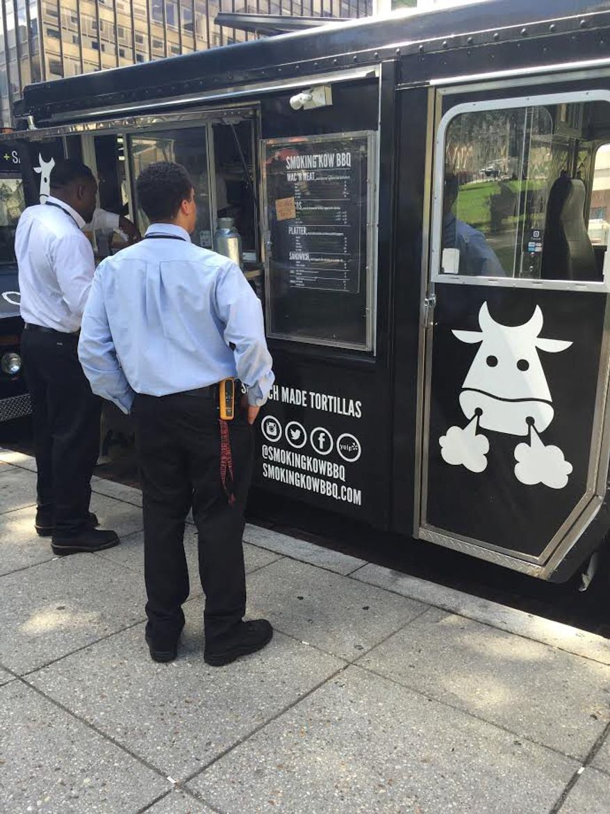 Customers check out the menu at the Smoking Kow Barbeque food truck in Farragut Square. A second Smoking Kow truck is expected late this summer. (Julia Porterfield /The Washington Times)