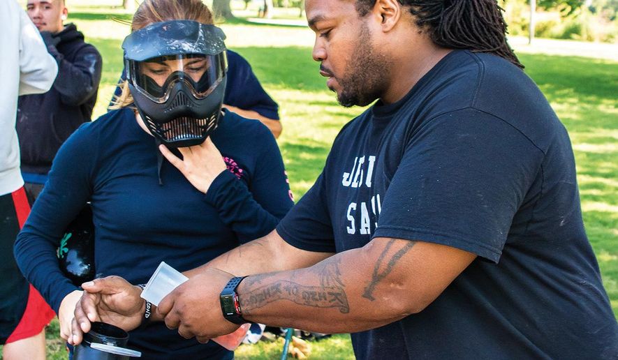 In this Aug. 8, 2016 photo, Kilie Law, gets the hopper on her paint ball gun filled by group mentor Charles Larry before the start of a paint ball match during a XCP Young Guns youth group meeting in Rock Falls, Ill. The group provides youth with a safe and fun activity in the controlled environment of a portable paint ball course. (Michael Krabbenhoeft/The Daily Gazette via AP)