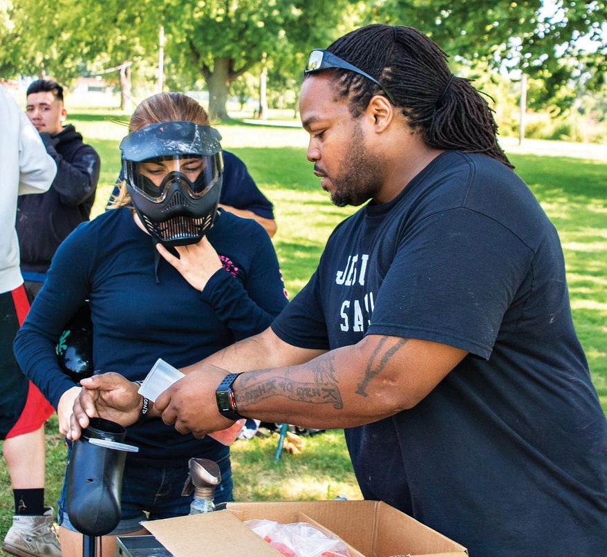 In this Aug. 8, 2016 photo, Kilie Law, gets the hopper on her paint ball gun filled by group mentor Charles Larry before the start of a paint ball match during a XCP Young Guns youth group meeting in Rock Falls, Ill. The group provides youth with a safe and fun activity in the controlled environment of a portable paint ball course. (Michael Krabbenhoeft/The Daily Gazette via AP)
