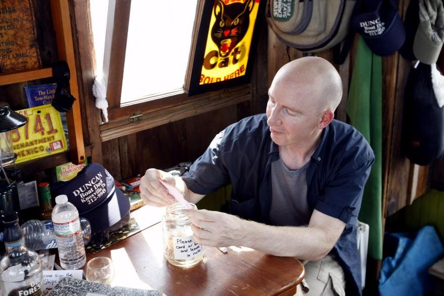 In this Aug. 8, 2016 photo, ships' mate Adrian Nankivell reads through handwritten messages left during an open house of the shantyboat Dotty, which is floating down the Tennessee River this summer as part of an oral history project called "A Secret History of American River People." in Florence, Ala. Smack dab in the middle of the Tennessee River near Muscle Shoals, Alabama, a recreated relic of river history is stuck like a catfish on a line, its anchor snagged on God only knows what at the bottom of the river. The shantyboat Dotty is a floating art project crafted by California-based artist Wes Modes.(Dennis Pillion/AL.com via AP)