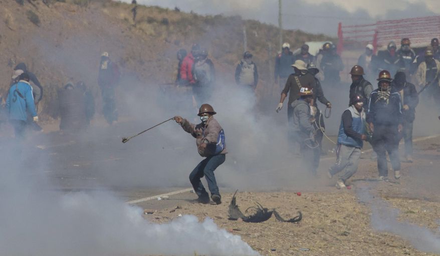Independent miners clash with the police as they run from clouds of tear gas during protests in Panduro, Bolivia, Thursday, Aug. 25, 2016. Thousands of independent miners continued their protests with roadblocks which precipitated the clashes as the police attempted to dislodge them. (AP Photo/Juan Karita)