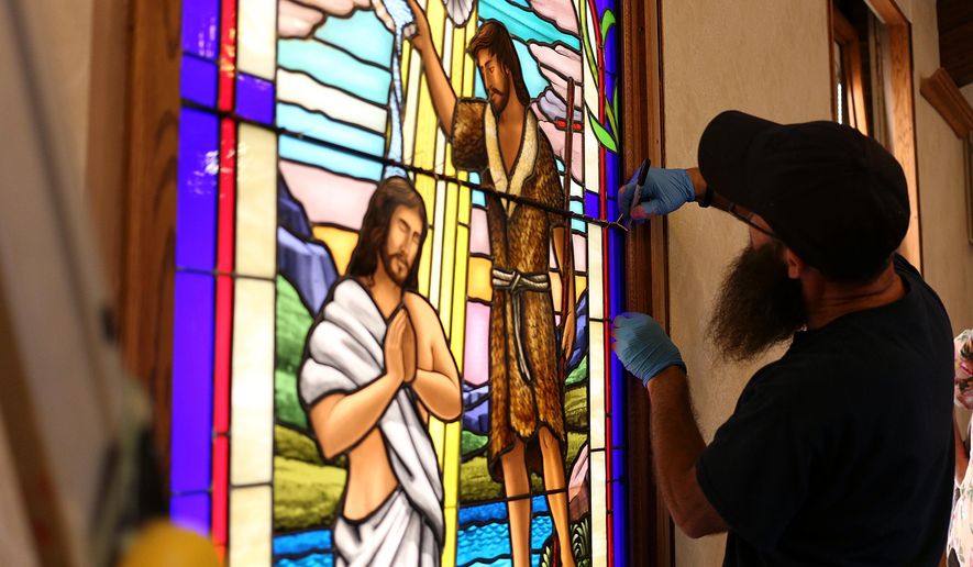 Ruben Llano works on the installation of a handmade glass window at the Addison Congregational Church, Thursday, Aug. 25, 2016, in Addison Mich. (Samantha Madar/Jackson Citizen Patriot via AP)