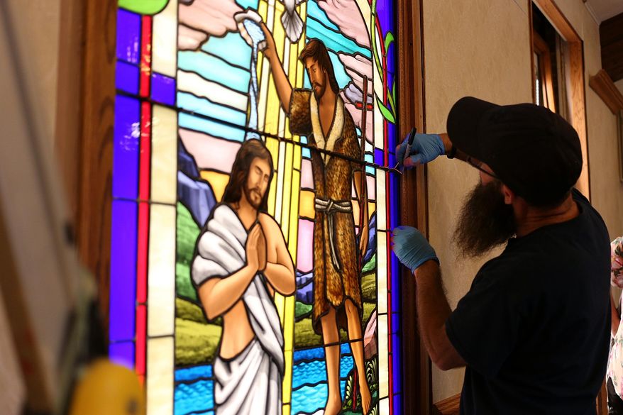 Ruben Llano works on the installation of a handmade glass window at the Addison Congregational Church, Thursday, Aug. 25, 2016, in Addison Mich. (Samantha Madar/Jackson Citizen Patriot via AP)