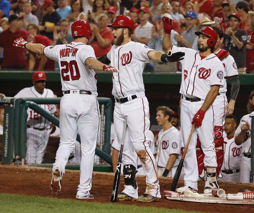 Washington Nationals Daniel Murphy, left, is greeted by teammates Bryce Harper, center, and Anthony Rendon, right, after hitting a solo home run off Colorado Rockies starting pitcher Jeff Hoffman during the fifth inning of a baseball game at Nationals Park, Friday, Aug. 26, 2016, in Washington. (AP Photo/Pablo Martinez Monsivais)