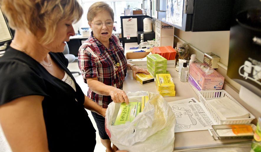 This photo taken Aug. 15, 2016, shows Bellefonte Area School District nurses Karen Truesdale and Val Fulton separating EpiPens to go to the different buildings. Truesdale knows how to save lives. It’s something the Bellefonte Area School District certified school nurse has done before. And when it comes to school nurses, she, alongside fellow certified school nurse Val Fulton, and a group of aides prove the job is more than bandaging up students with scraped knees, and sending sick kids home. (Abby Drey/Centre Daily Times via AP)