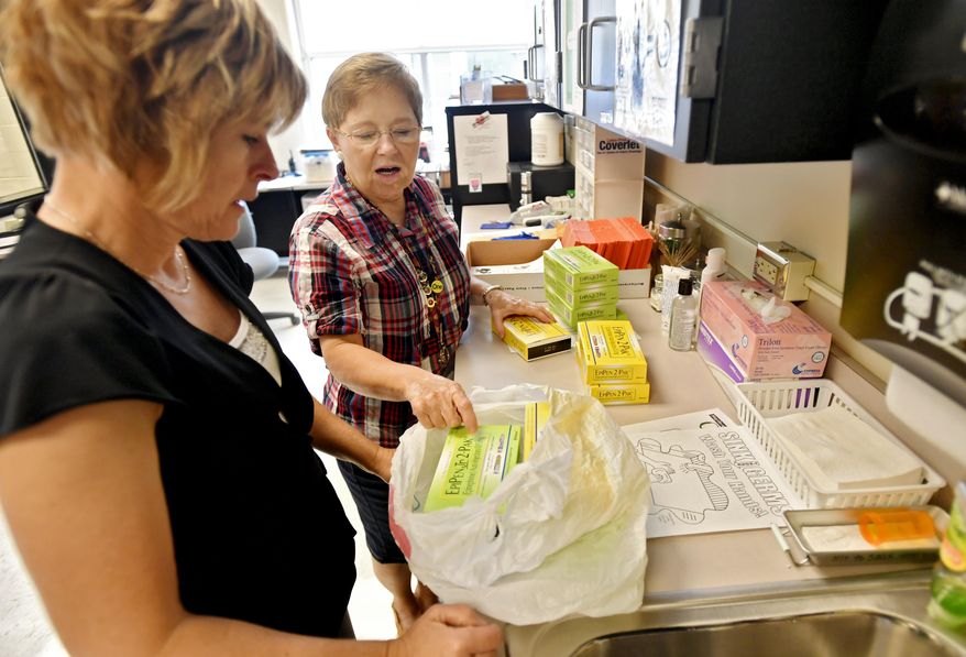 This photo taken Aug. 15, 2016, shows Bellefonte Area School District nurses Karen Truesdale and Val Fulton separating EpiPens to go to the different buildings. Truesdale knows how to save lives. It’s something the Bellefonte Area School District certified school nurse has done before. And when it comes to school nurses, she, alongside fellow certified school nurse Val Fulton, and a group of aides prove the job is more than bandaging up students with scraped knees, and sending sick kids home. (Abby Drey/Centre Daily Times via AP)