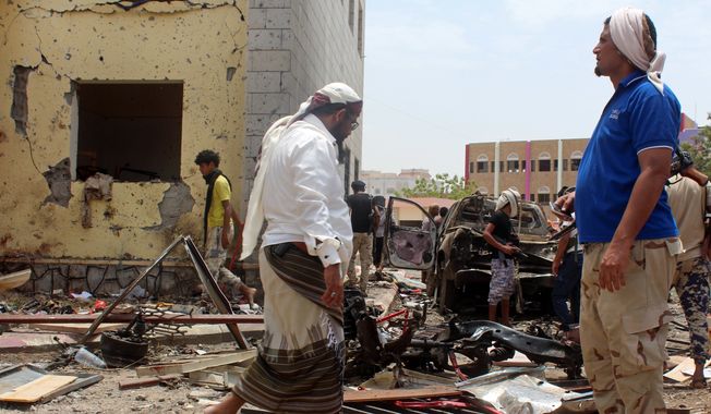 Fighters loyal to the government gather at the site of a suicide car bombing in Yemens southern city of Aden, Yemen, Monday, Aug. 29, 2016. The bombing claimed by the Islamic State group in Aden has killed over 50 pro-government troops who had been preparing to travel to Saudi Arabia to fight Houthi rebels in Yemens north. Yemen is embroiled in a civil war pitting the internationally recognized government and a Saudi-led coalition against the Shiite Houthi rebels, who are allied with army units loyal to a former president. The fighting has allowed al Qaeda and an IS affiliate to expand their reach, particularly in the south. (AP Photo/Wael Qubady)