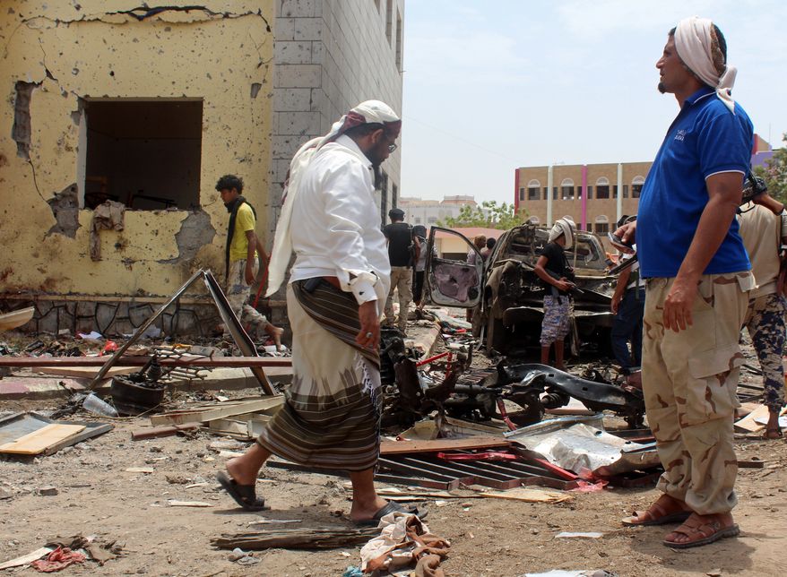 Fighters loyal to the government gather at the site of a suicide car bombing in Yemens southern city of Aden, Yemen, Monday, Aug. 29, 2016. The bombing claimed by the Islamic State group in Aden has killed over 50 pro-government troops who had been preparing to travel to Saudi Arabia to fight Houthi rebels in Yemens north. Yemen is embroiled in a civil war pitting the internationally recognized government and a Saudi-led coalition against the Shiite Houthi rebels, who are allied with army units loyal to a former president. The fighting has allowed al Qaeda and an IS affiliate to expand their reach, particularly in the south. (AP Photo/Wael Qubady)