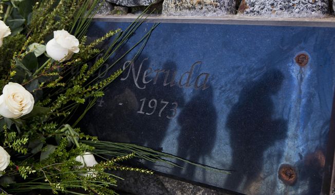 Journalists are reflected on the tombstone of Chile&#x27;s Nobel Prize-winning poet Pablo Neruda after he was reburied at his home, now a museum, on Isla Negra, Chile, Tuesday, April 26, 2016. Neruda&#x27;s body was exhumed in 2013 for a fourth time in an effort to clear up four decades of suspicion about how the poet died in the days after Chile&#x27;s military coup. The results of the analysis will be delivered on May 5. (AP Photo/Esteban Felix)