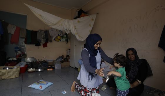 A woman plays with a child at an abandoned hospital wing, which is used as a makeshift shelter for about 150 Syrian refugees in Athens, Wednesday, Aug. 31, 2016. Over 59,000 people remain stranded in the country, most in army-built camps on the mainland and about 7,800 refugees are receiving hotel vouchers or live in vacant apartments. (AP Photo/Thanassis Stavrakis)