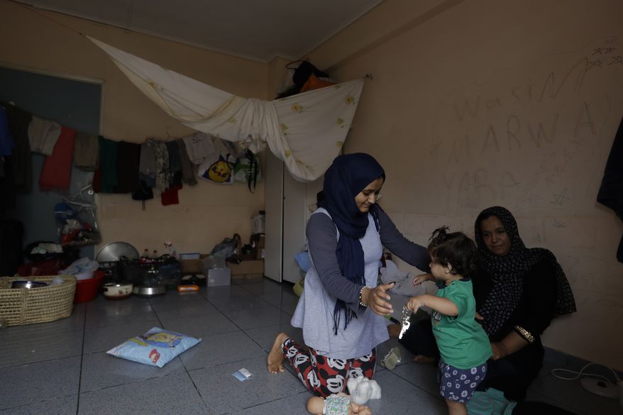 A woman plays with a child at an abandoned hospital wing, which is used as a makeshift shelter for about 150 Syrian refugees in Athens, Wednesday, Aug. 31, 2016. Over 59,000 people remain stranded in the country, most in army-built camps on the mainland and about 7,800 refugees are receiving hotel vouchers or live in vacant apartments. (AP Photo/Thanassis Stavrakis)