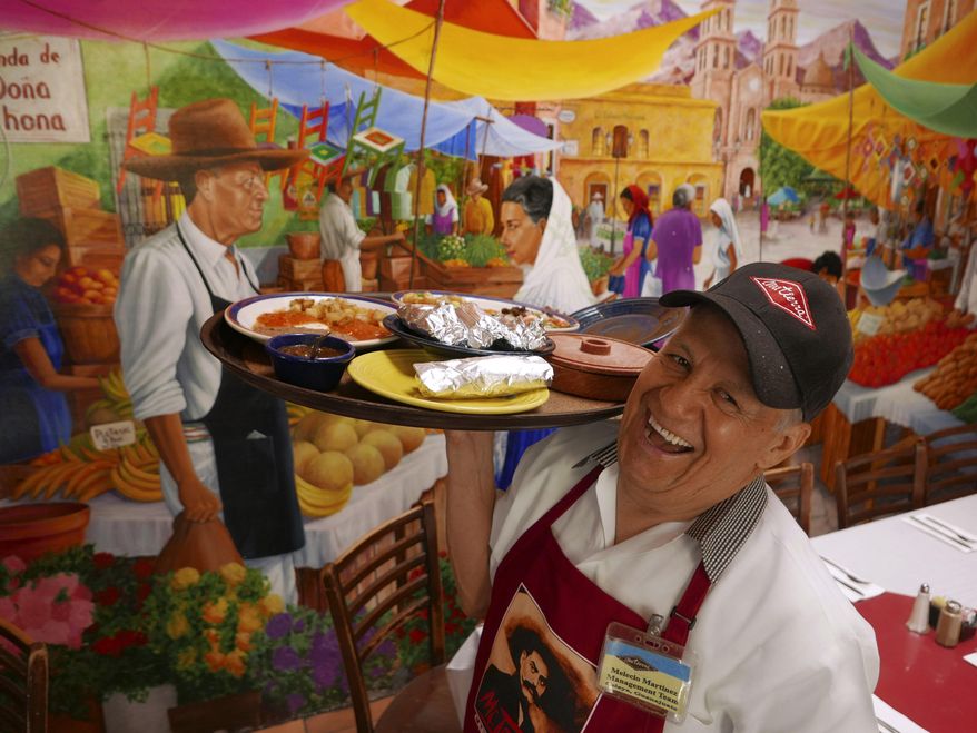 ADVANCE FOR USE MONDAY, SEPT. 5 - In this July 19, 2016 photo, Melecio Martinez, the morning manager at Mi Tierra restaurant and has worked at the restuarant for 38 years, carries out an order in San Antonio. It all started in 1941, when Pedro Cortez and his wife, Cruz, bought a little three-table cafe at the San Antonio farmers market. Today, Mi Tierra seats 650 people in a vast space that has seen countless quinceaneras and graduations celebrated, much political campaigning and a little skullduggery, visiting celebrities galore and an endless stream of tourists from around the world. (Billy Calzada/The San Antonio Express-News via AP)