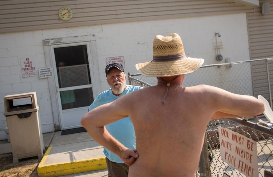ADVANCE FOR USE MONDAY, SEPT. 5, 2016, AND THEREAFTER- In this June 10, 2016, photo, Cherry Lane Nudist Resort owner Dennis Bevis talks with a resident outside of the pool at Cherry Lane Nudist Resort in North Adams, Mich., just south of Jackson. (Ryan Garza/Detroit Free Press via AP)