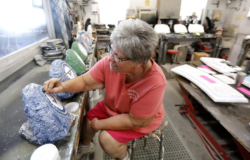 In this Monday, Aug. 22, 2016 photo, Carol Willenborg, of Willenborg Lawn Ornaments, paints lettering on a lawn ornament in New Vienna, Iowa. (Mike Burley/Telegraph Herald via AP)