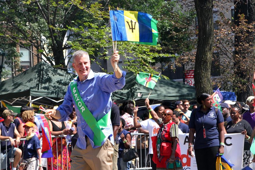 FILE - In this Sept. 7, 2015 file photo, Mayor Bill de Blasio, foreground, makes his way along Eastern Parkway in the Brooklyn borough of New York as he takes part in the West Indian Day Parade. For years, there have been complaints about safety at J'ouvert a big, joyous carnival celebrating Caribbean culture held before dawn each Labor Day on the streets of New York City. But after an aide to New York's governor was killed by a stray bullet last year, authorities are taking unprecedented precautions. (AP Photo/Tina Fineberg)