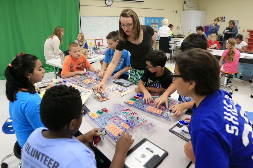 Fifth grade teacher Suni Haberland provides batteries for a makerspace workstation at Bluejacket Flint Elementary School in Kansas City, Kan., Thursday, Aug. 25, 2016. The "makerspace" movement sweeping through K-12 schools across the United States encourages collaborative, creative, student-driven education. But there are concerns about how already-busy teachers can incorporate a counterpoint to schools' increasingly test-based curriculums and emphasis on reading, writing and arithmetic. (AP Photo/Orlin Wagner)
