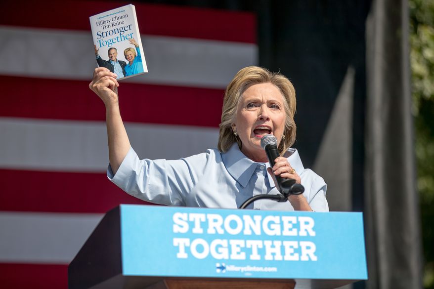Democratic presidential candidate Hillary Clinton holds up a book entitled "Stronger Together" as she speaks at the 11th Congressional District Labor Day festival at Luke Easter Park in Cleveland, Ohio, Monday, Sept. 5, 2016. (AP Photo/Andrew Harnik)