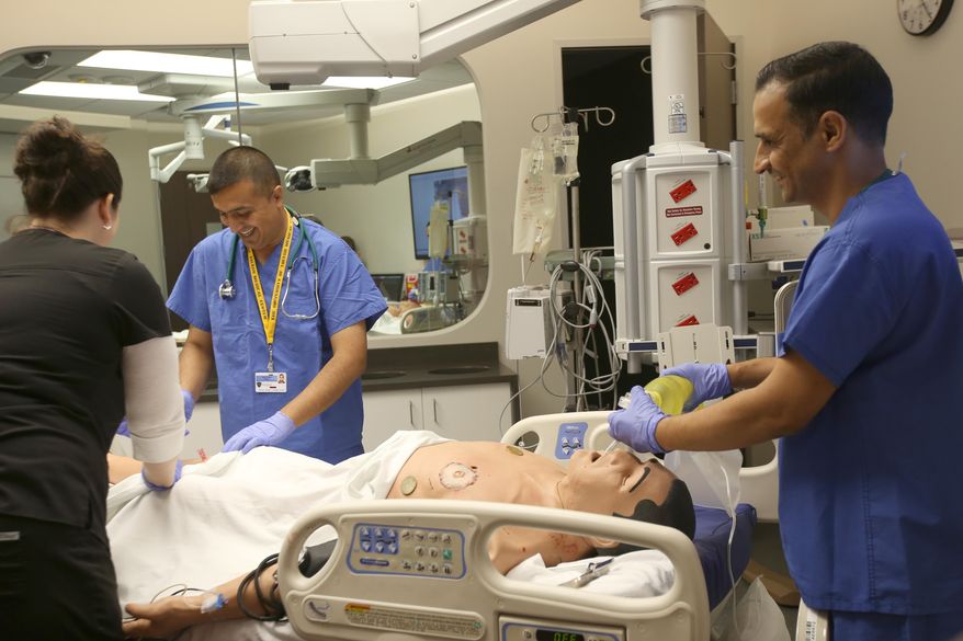 ADVANCE FOR WEEKEND EDITIONS, SEPT. 3-5 - In this Tuesday, Aug. 23, 2016 photo, Dr. Qusay Al Obaidi, center, and Dr. Saad Mijbad, right, work with registered nurse Katie Bush, left, as they intubate and treat a teaching dummy who was set up to simulate a gunshot victim at the Interprofessional Immersive Simulation Center at the University of Toledo Medical College in Toledo, Ohio. Both doctors are from Iraq and are in the first week of a four week training program in emergency medicine. (Katie Rausch/The Blade via AP)
