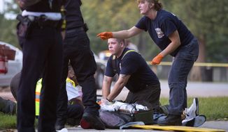 Members of the Chicago Fire Department work on a gunshot victim at the scene of a double shooting in Ogden Park Monday, Sept. 5, 2016, in the Englewood neighborhood of Chicago. Thirteen people were shot to death over the Labor Day weekend in Chicago, making it the deadliest holiday weekend of one of the deadliest summers the city has experienced in decades.  (Erin Hooley/Chicago Tribune via AP) ** FILE **