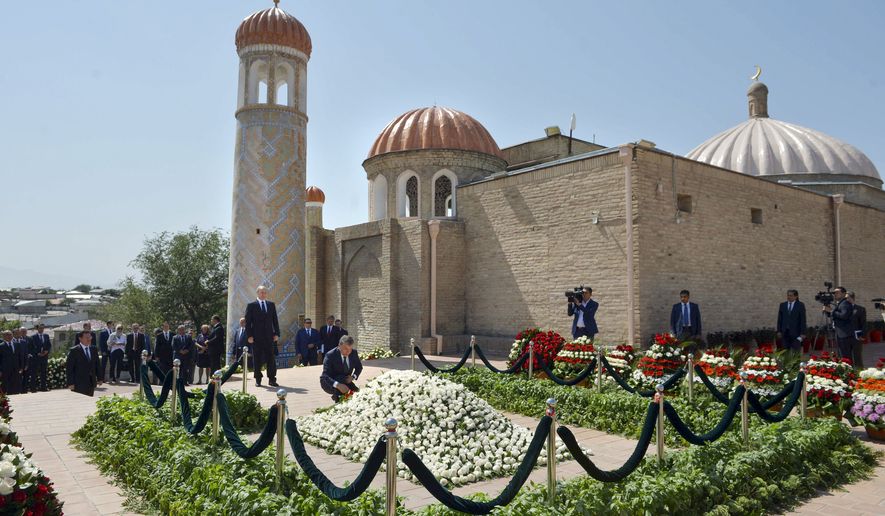Uzbekistan's Prime Minister Shavkat Mirziyayev, center, places flowers, as Russian President Vladimir Putin stands at left of him, during a minute of silence at a cemetery in Samarkand, Uzbekistan, Tuesday, Sept. 6, 2016. Putin arrived to express his condolences and visit a grave of Uzbekistan's President Islam Karimov in Samarkand. (Alexei Druzhinin/Sputnik, Kremlin Pool Photo via AP)