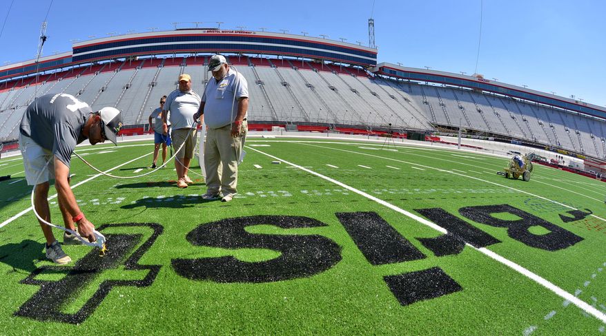 In this Sept. 3, 2016, photo, members of the University of Tennessee grounds crew paint the "Battle at Bristol" logo on the football field at Bristol Motor Speedway in Bristol, Tenn. The "Battle at Bristol" between Tennessee and Virginia Tech on Saturday has been discussed for two decades and was announced three years ago. But the transformation of Bristol Motor Speedway into a 150,000-seat football stadium that could host the largest crowd in NCAA history was completed in a matter of weeks. (Earl Neikirk/Bristol Herald Courier via AP)