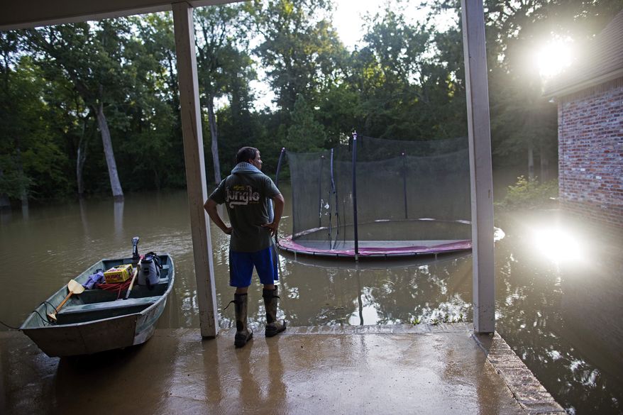 David Key looks at the back yard of his flooded home in Prairieville, La., Tuesday, Aug. 16, 2016. Key, an insurance adjuster, fled his home as the flood water was rising with his wife and three children and returned today to assess the damage. (AP Photo/Max Becherer)