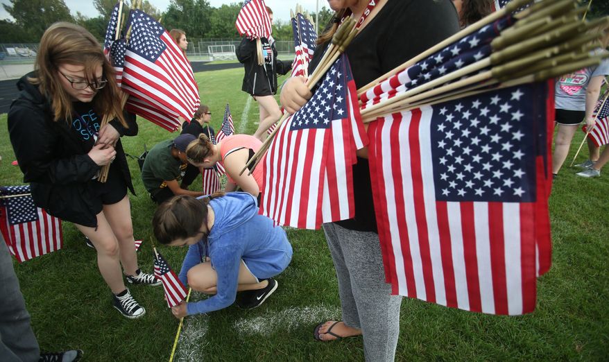 Students at Civic Memorial High School in Bethalto, Ill., push some of the 2,996 American flags into the football field Thursday, Sept. 8, 2016, for a Sept. 11 Memorial Ceremony in remembrance of the 15th anniversary of the terrorist attacks on America. Each flag represents one of the people who died in the attack. (John Badman/The Telegraph via AP)