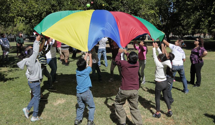 FILE - In this July 26, 2012 file photo children and adults uses a play parachute as part of an exercise activity during a wellness program run jointly by the La Familia Counseling Center INC., and the YMCA in Sacramento, Calif. Voters approved Proposition 63 in 2004 to provide funding for mental health services, but a California watchdog agency, the Little Hoover Commission, reported Thursday, Sept. 8, 2016, that 12 years after voters approved a 1 percent tax on millionaires, the state still can't readily show how the money is spent or who is helped. (AP Photo/Rich Pedroncelli, File)