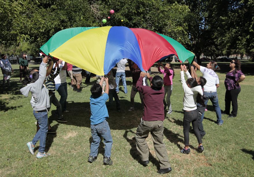 FILE - In this July 26, 2012 file photo children and adults uses a play parachute as part of an exercise activity during a wellness program run jointly by the La Familia Counseling Center INC., and the YMCA in Sacramento, Calif. Voters approved Proposition 63 in 2004 to provide funding for mental health services, but a California watchdog agency, the Little Hoover Commission, reported Thursday, Sept. 8, 2016, that 12 years after voters approved a 1 percent tax on millionaires, the state still can't readily show how the money is spent or who is helped. (AP Photo/Rich Pedroncelli, File)