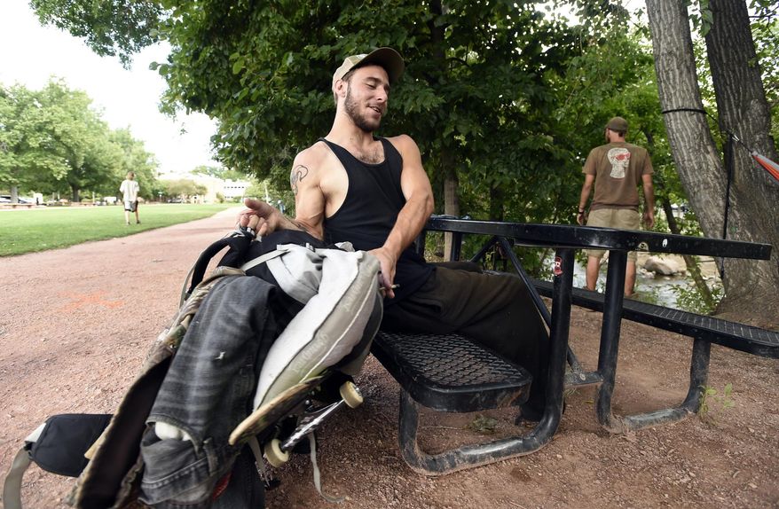 ADVANCE FOR WEEKEND EDITIONS SEPT 10-11 - In this Aug. 31, 2016 photo, Nate Brown, 21, lifts his bag of belongings to the picnic table while hanging out by the Boulder Creek in Boulder, Colo. Though Boulder hasn't conducted a formal study to confirm it, a general feeling persists, particularly among cops, business owners and longtime residents, that since pot was legalized, the city has attracted a new brand of homeless person: younger and sometimes unhoused by choice; more prone to drug abuse and public disruptiveness; and less tenured in town, so therefore less invested, on average, in community vitality. (Jeremy Papasso/Daily Camera via AP)
