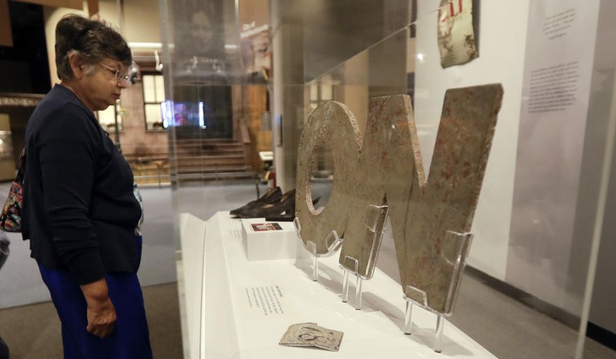 In this Friday, Sept. 9, 2016 photo, a visitor at the New York State Museum in Albany, N.Y., looks at items from a new component of the museum&#39;s exhibit of the Sept. 11, 2001, terror attack on the World Trade Center. The &amp;quot;World Trade Center Survivors&amp;quot; addition tells the stories of three of the thousands of people who survived the 9/11 attack in Lower Manhattan. Objects used to tell those stories include a pair of shoes, a cellphone and a stairway evacuation sign from one of the fallen Twin Towers. (AP Photo/Mike Groll)