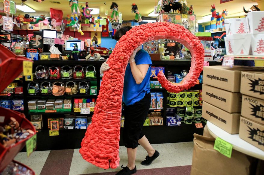 ADVANCE FOR WEEKEND EDITIONS, SEPT. 10-11 - In this Aug. 24, 2016 photo, Jackie Sugita carries a tentacle display to the garbage at Archie McPhees in the Wallingford neighborhood of Seattle. Yodeling pickles, bonnets for cats, Bigfoot action figures and the other wacky creations are sold at the store. (Kevin Clark/The Herald via AP)