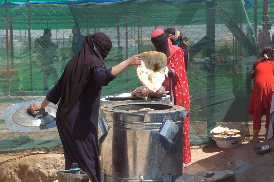 An Iraqi woman bakes bread in makeshift ovens at a U.N. refugee camp in Fallujah, Iraq. Thousands of Iraqi civilians flooded camps around Fallujah after U.S.-backed Iraqi forces ousted Islamic State from the city in late June. (Carlo MuNoz/The Washington Times)