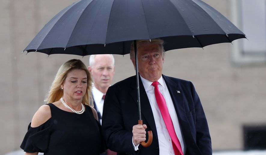 FILE - In this Aug. 24, 2016 file photo, Republican presidential candidate Donald Trump walks in the rain with Florida Attorney General Pam Bondi as they arrive at a campaign rally in Tampa, Fla. Facing the toughest stretch of her campaign, Hillary Clinton is trying to deflect attention back onto her rival Donald Trump, with a new push to highlight complaints surrounding his now-defunct Trump University, and allegations of pay-to-play involving Florida Attorney General Pam Bondi.(AP Photo/Gerald Herbert, File)