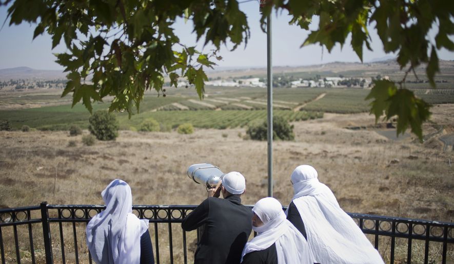 A Druze family, celebrating the Eid al-Adha holiday, look towards Syria&#39;s Quneitra province as they visit an observation point in the Israeli-controlled Golan Heights, Tuesday, Sept. 13, 2016. Israel is denying Syrian government claims that its forces shot down a warplane and a drone near the Israeli-controlled part of the Golan Heights. Israeli warplanes have conducted several air raids on Syrian army positions over the past weeks after stray shells hit the Israeli-occupied area. (AP Photo/Ariel Schalit)